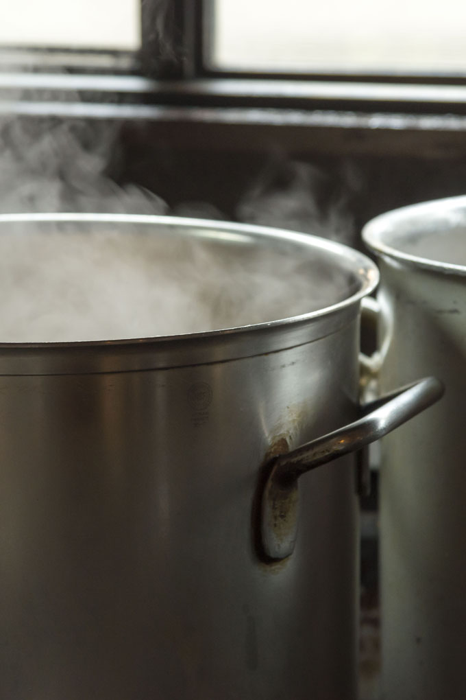 Tall, metal, steaming stock pot, with another identical stock pot next to it.