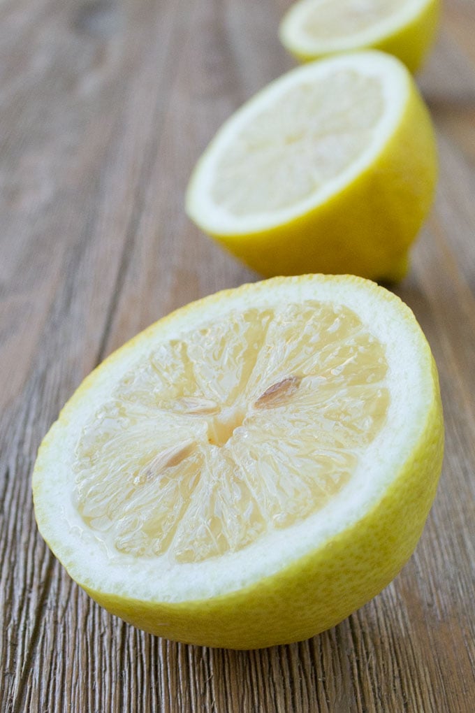 Three lemon halves, set a a row on a wooden surface.