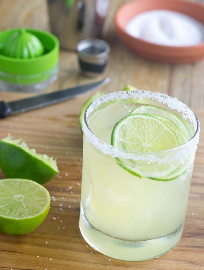 Classic Margarita in a rocks glass, with salt on the rim and lime slices.