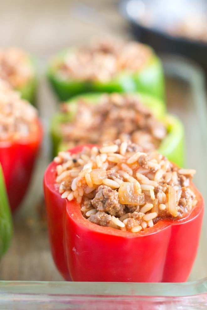 Red and green bell peppers with the tops cut off stuffed with ground beef and rice.