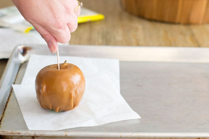 Inserting stick into caramel apple