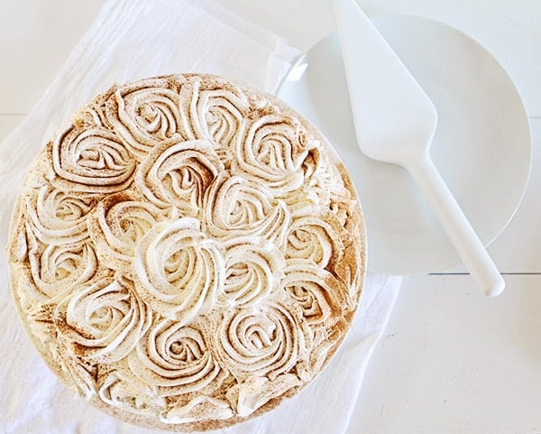 Pumpkin pie with piped roses dusted with cinnamon covering the top.