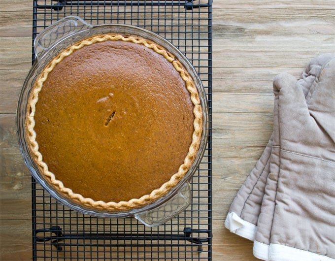 Classic Pumpkin Pie in a glass pie dish resting on a cooling rack.