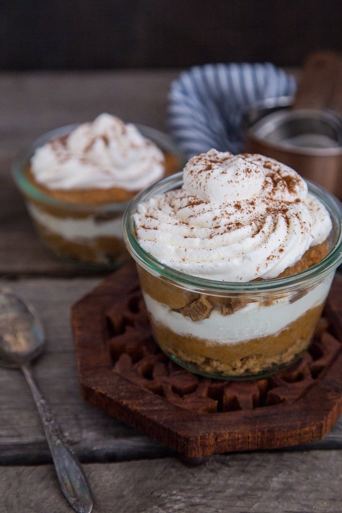 Pumpkin Pie Trifle in glass dish on a wooden trivet.