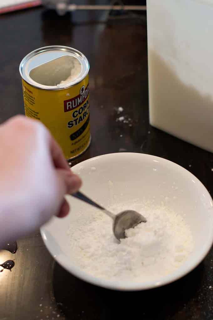 Powdered sugar and cornstarch being stirred together in a bowl.