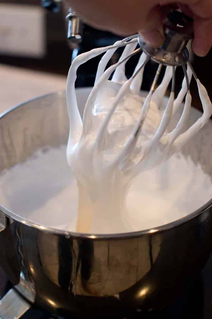 Marshmallow mixture hanging from whisk attachment into bowl.