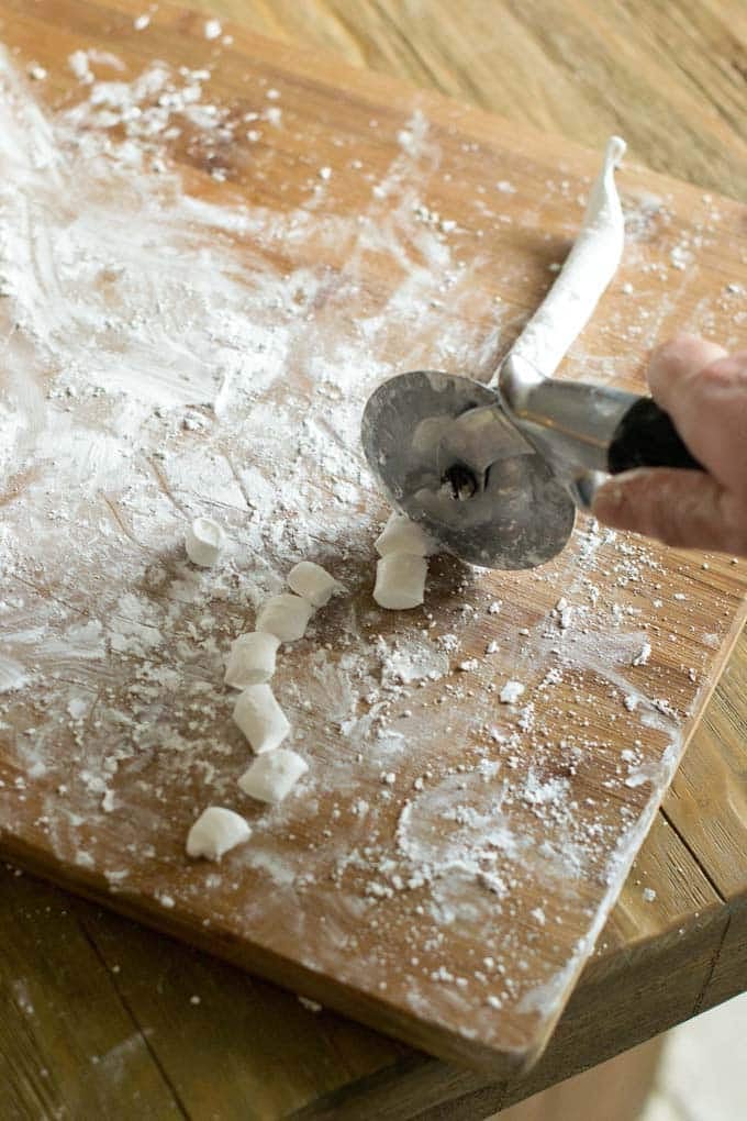 Cut with a pizza cutter Cut lines of marshmallow with a pizza cutter on a dusted cutting board.