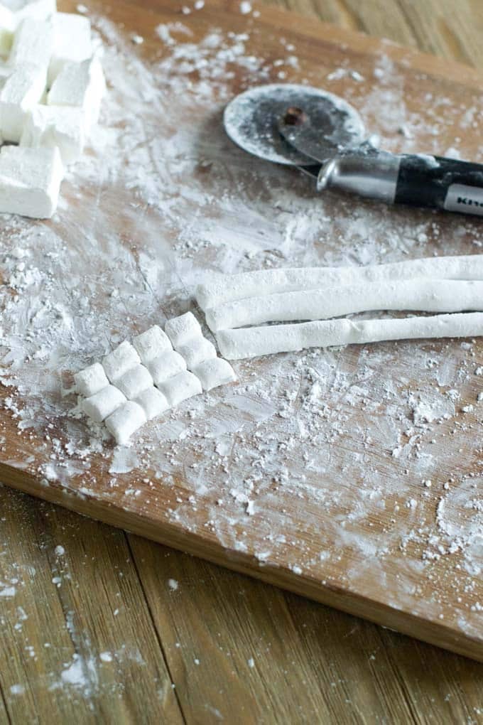 Making mini marshmallows by cutting on a wooden board.