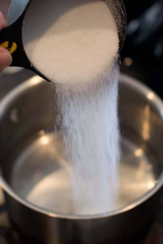Sugar being poured into a saucepan. 
