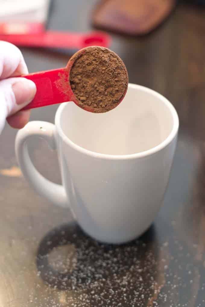 Adding cocoa powder to white mug.