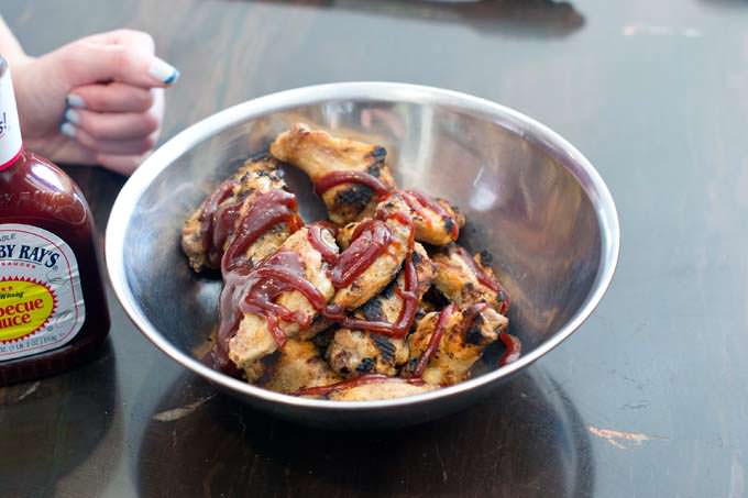 Chicken wings in a bowl, drizzled with BBQ sauce.