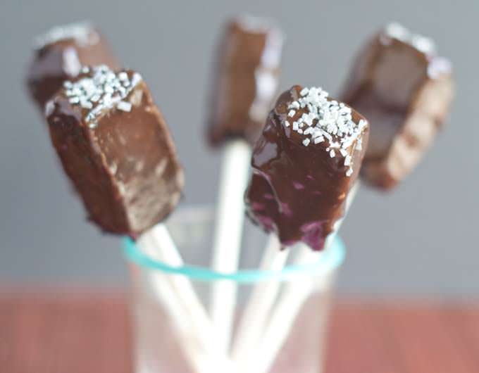Brownie pops with sprinkles held upright in a glass.