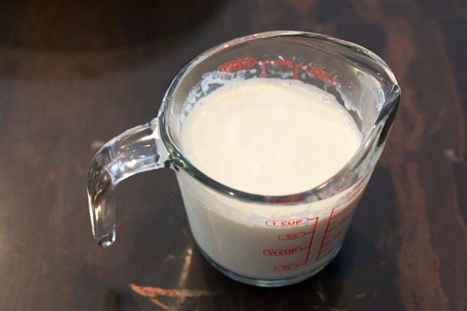 Warm heavy cream in glass measuring cup