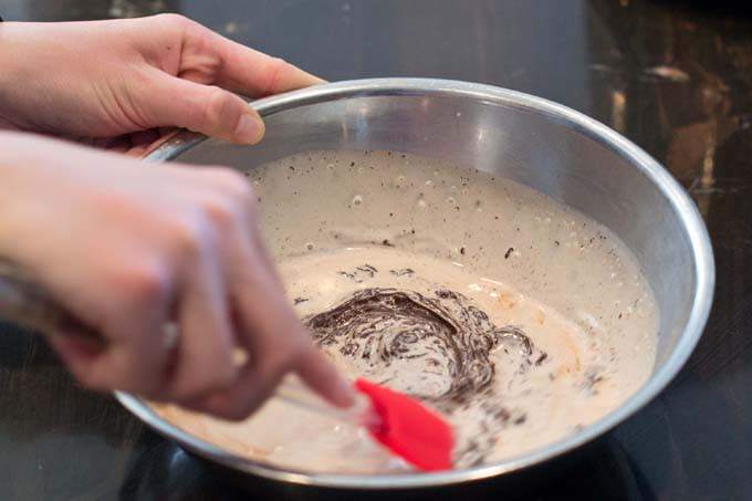 Stirring chocolate and cream together in metal bowl