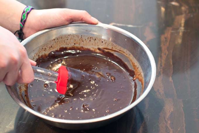 Chocolate ganache being stirred in a bowl.