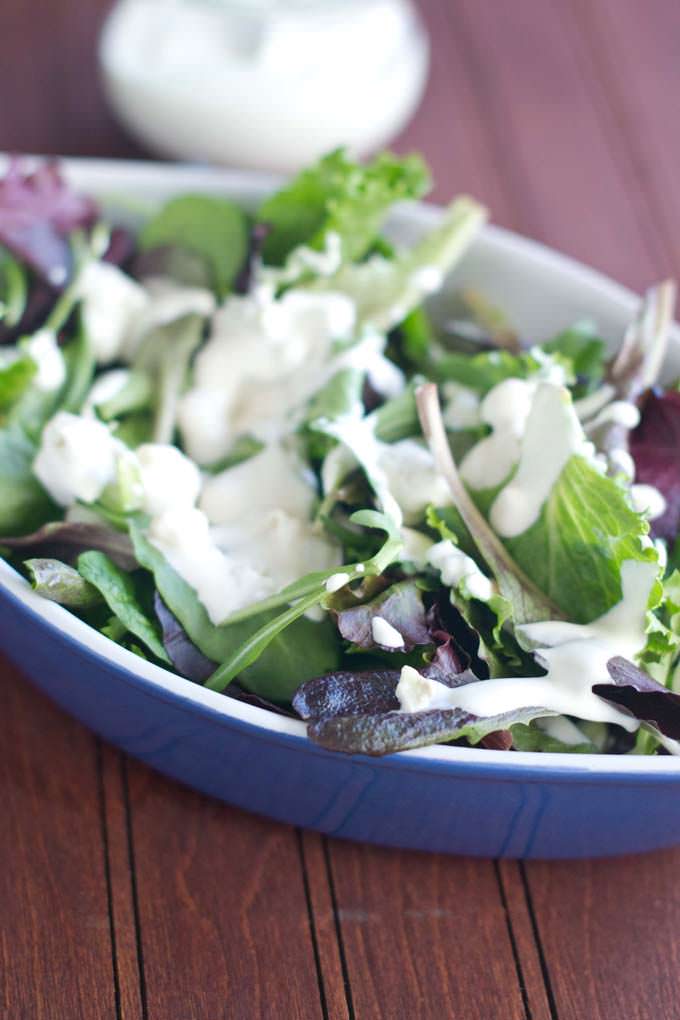 blue dish filled with salad greens drizzled with cream blue cheese dressing.