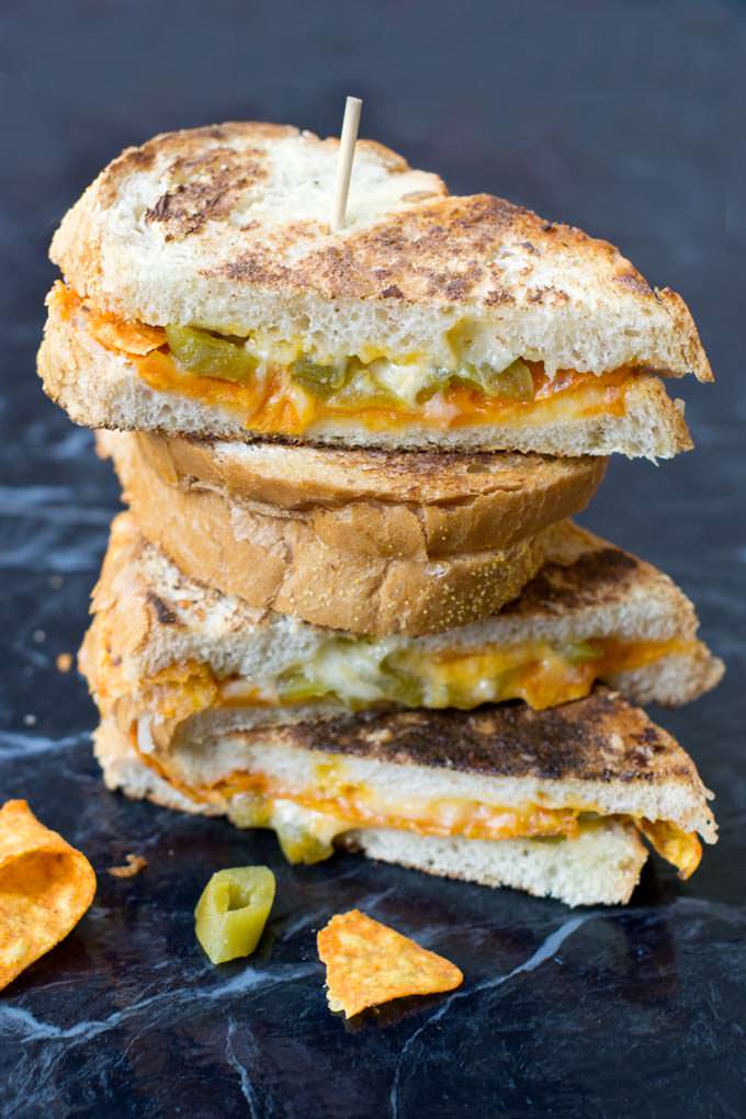 Nacho Grilled Cheese Sandwiches, cut in half and stacked on top off each other with a bamboo skewer down the middle.