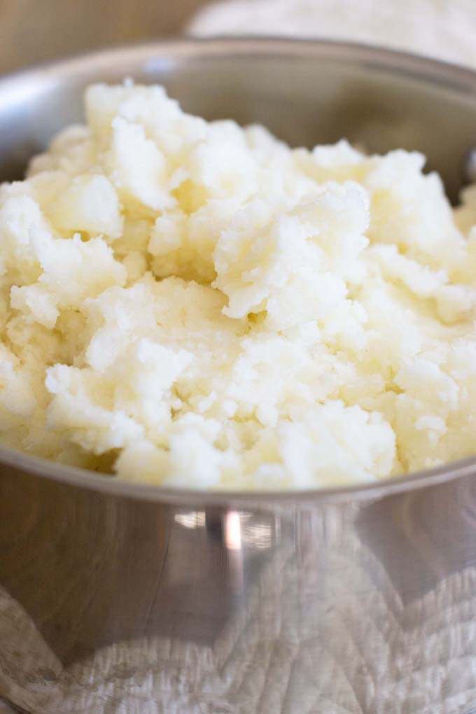 Close up photo of mashed potatoes in a metal bowl.