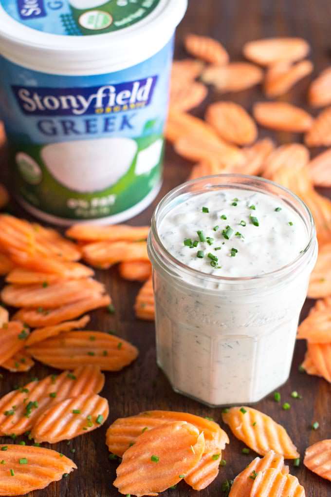 Homemade Ranch Dressing in glass jar, greek yogurt container ad carrot slices around.