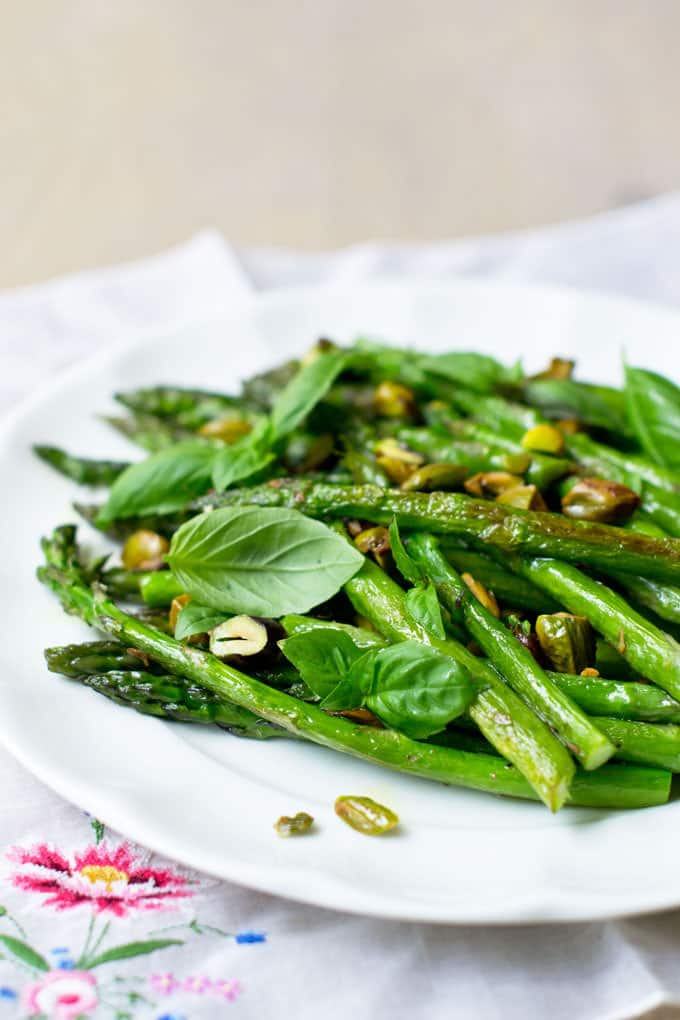 Roasted Asparagus with Basil and Pistachios on a white plate.