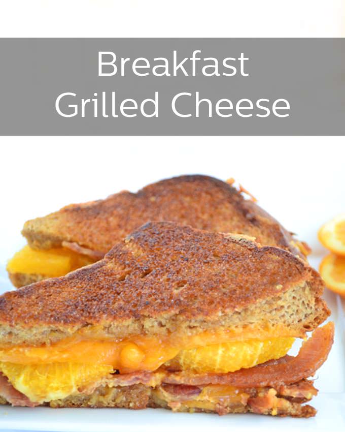 A grilled cheese sandwich made of grilled bread, orange cheddar cheese, orange slices and bacon on a white plate with a white background