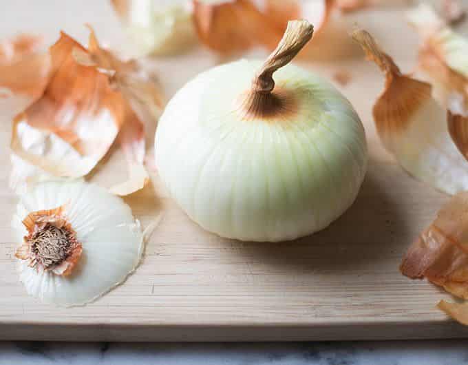 Peeled Vidalia Onion on a cutting board surrounded by the peels.