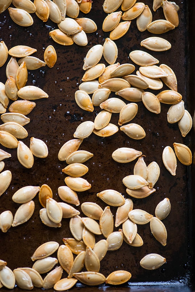 Salted pumpkin seeds on a baking sheet.