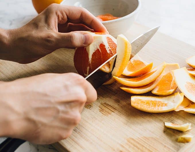 Slice rind off orange 