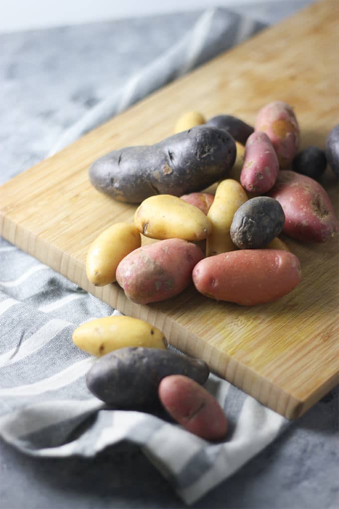 Various types of potatoes on a wooden board.