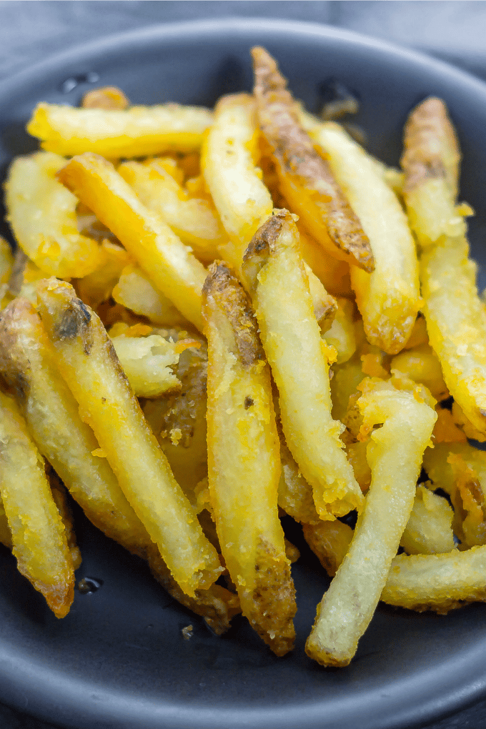 Close up of homemade french fries on a dark plate. 