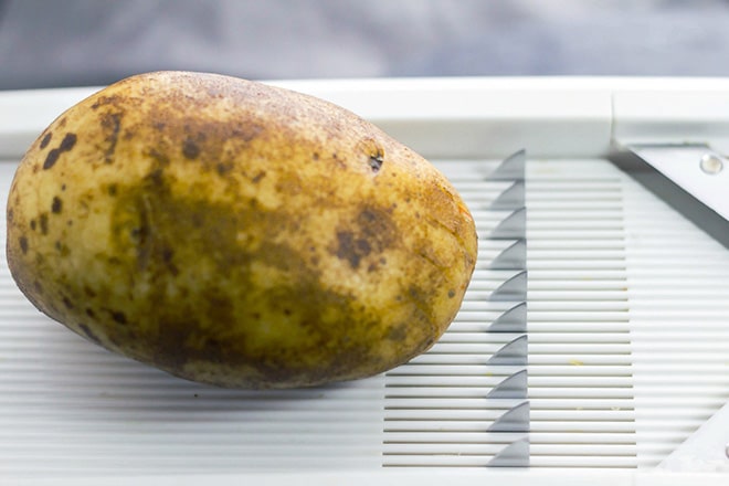 Potato on mandolin slicer.