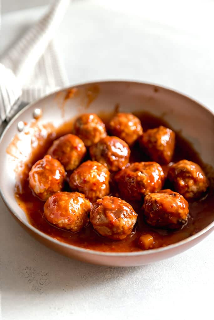 Skillet filled with meatballs tossed in BBQ sauce.