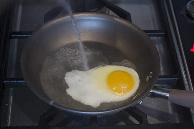 add a drizzle of hot tap water to the egg in the pan