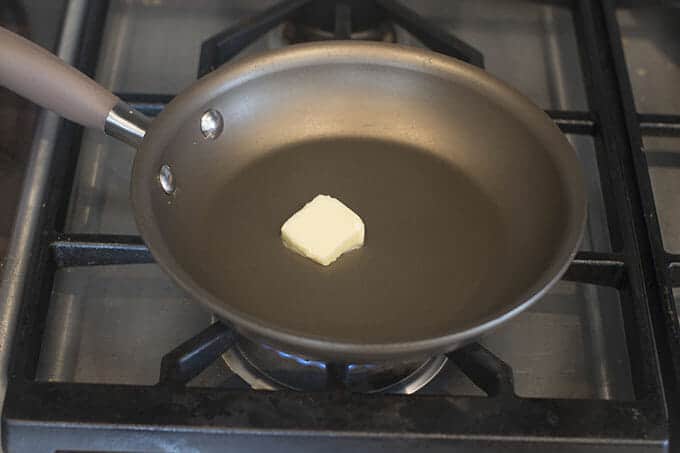 Pat of butter melting in pan on a stove.