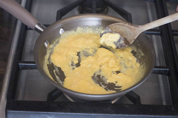 Eggs being stirred in a pan as they cook and solidify.