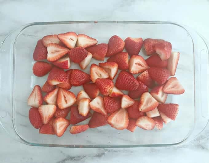 Fresh, halved strawberries in a glass dish.