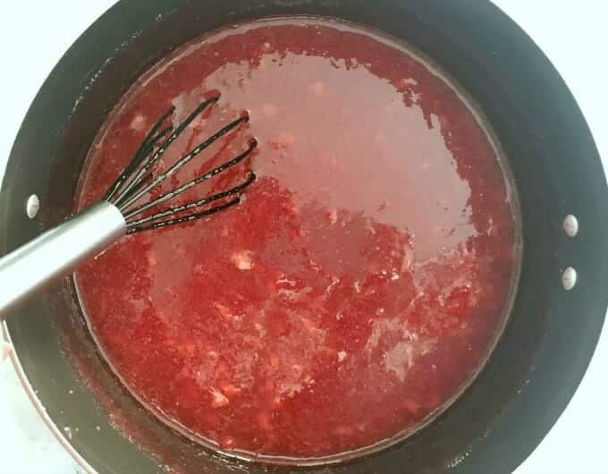 Jam ingredients in a large pot with a whisk.