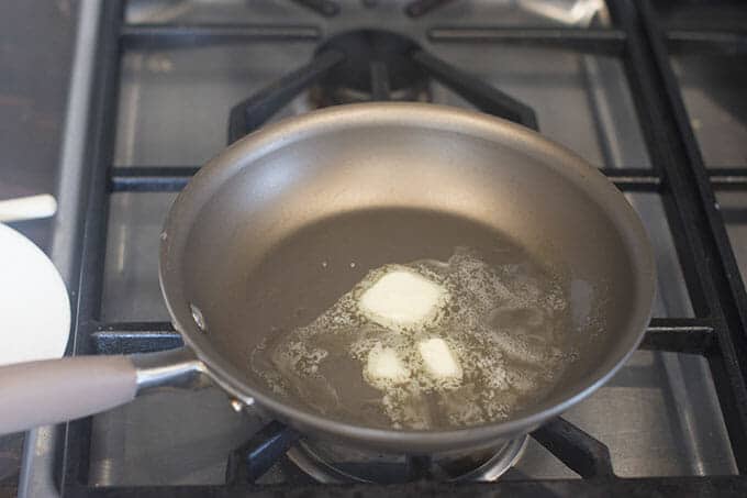 Butter melting in pan on stovetop.