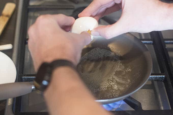 An egg being cracked over a pan.