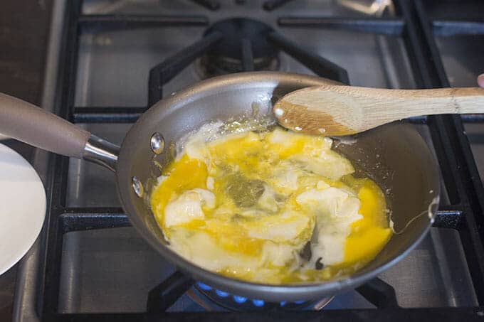 Stirring eggs while they cook in a pan.