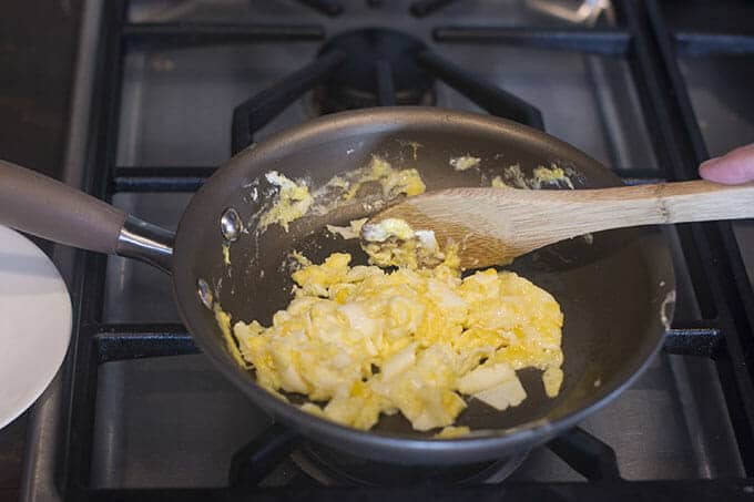 Stirring scrambled eggs until the yolks are set.