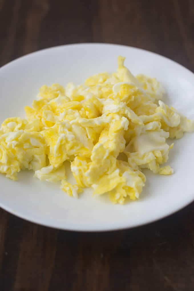 Hard scrambled eggs on white plate.