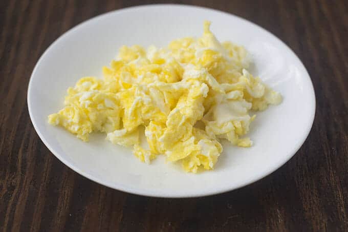 Hard scrambled eggs on a white plate.