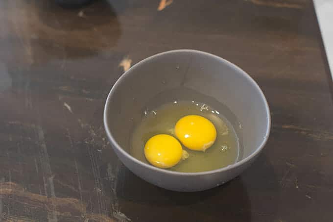 Two raw eggs in a gray bowl.