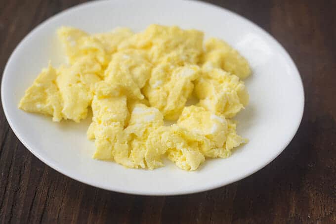 White plate with scrambled eggs.