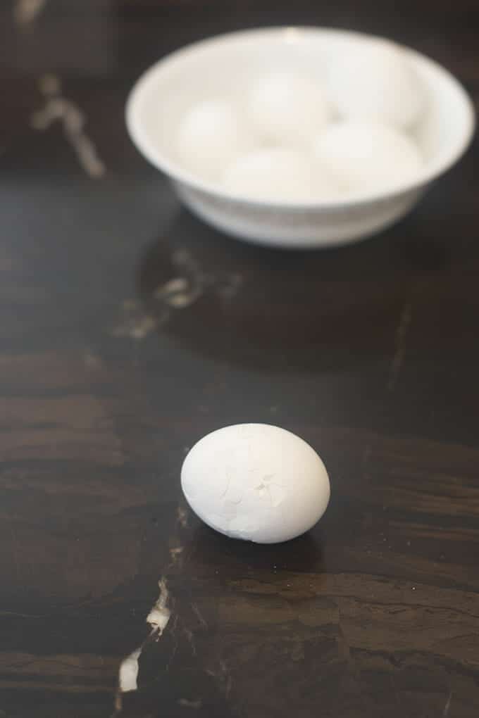 Covered in a web of cracks. Hard cooked egg on counter that is covered in cracks.