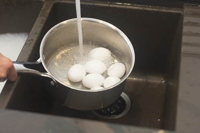 Water from tap filling a saucepan with eggs in it.
