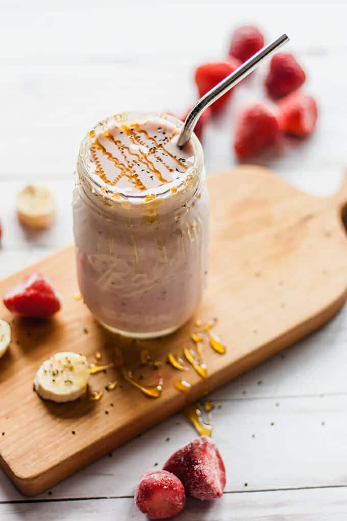 Strawberry banana smoothie in a mason jar, drizzled with honey.