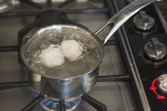 Two eggs cooking in boiling water.