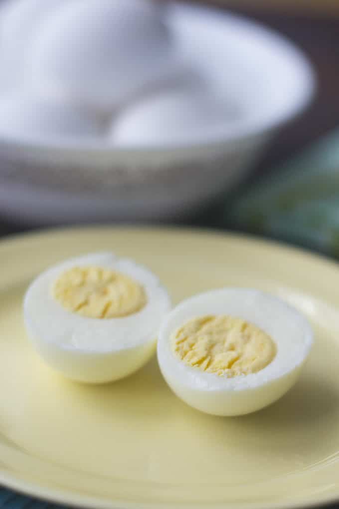 Steamed egg cut in half to show light yellow yolk, on a cream colored plate.